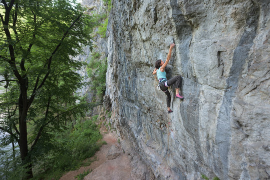 Woman rock climbing on steep wall on a summer day