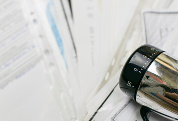 The concept of deadline. Mechanical timer at zero against the background of scattered documents.