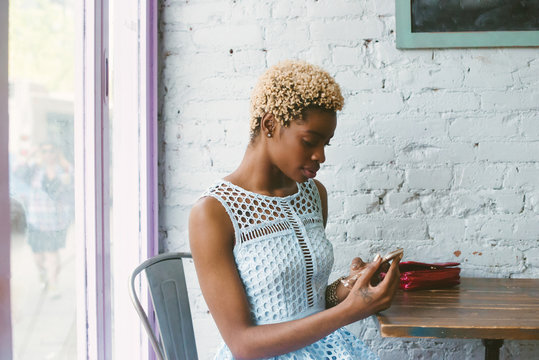 Trendy young woman waiting in cafe with phone