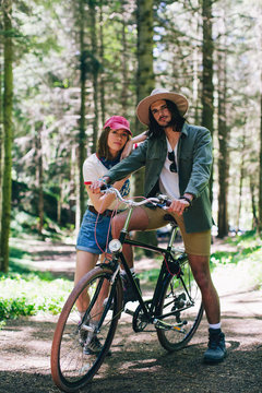 Young couple riding a bike on the woods.