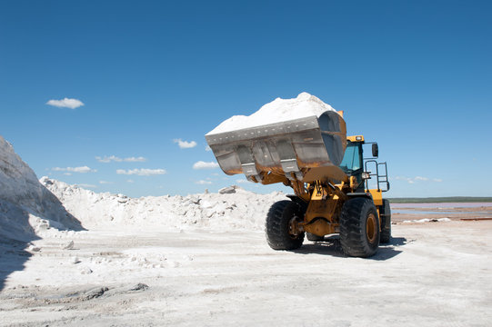 Caterpillar on wheel moves raw salt against blue sky in a salt mine in  Argentina.
