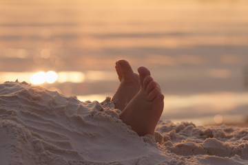 Closeup child kid feet on white sand beach.