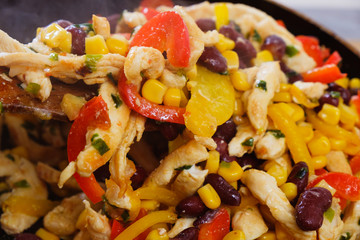 Pan with roasted vegetables and chicken for burritos close-up of cooking burrito.