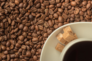 scattered grains of coffee on a wooden table with a white cup of coffee