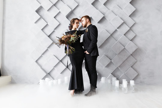 Bride and groom portrait in studio. Isolated on gray geometric background. Dry ice smoke on floor