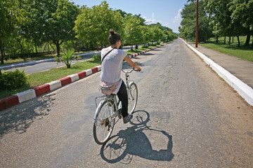 Young female backpacker cycles down the roads in Bagan, Burma