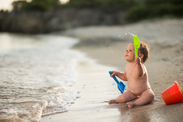 Baby playing near sea with beach toys