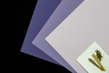 Cone shaped rolling paper with loose medical marijuana and joint on an ultraviolet monocromatic scale on black background