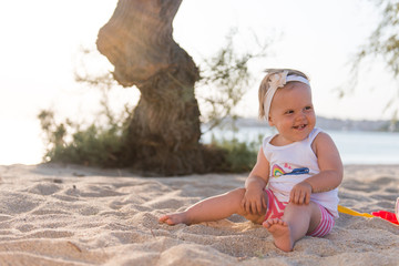 Caucasian baby girl playing in sand beach under tree