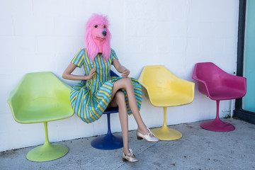 Mannequin woman posed in mid-century modern chair wearing dog mask