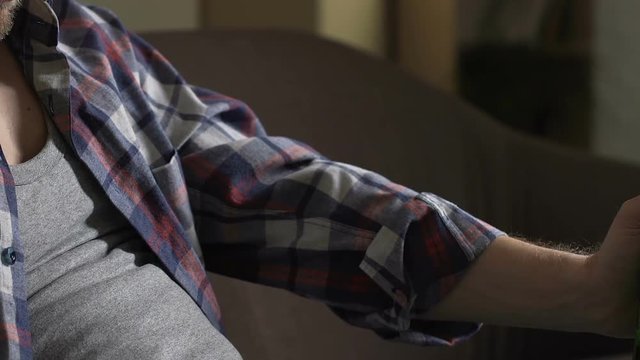 Drunk man in his 40s sitting on couch with beer bottle and sleeping, alcoholism