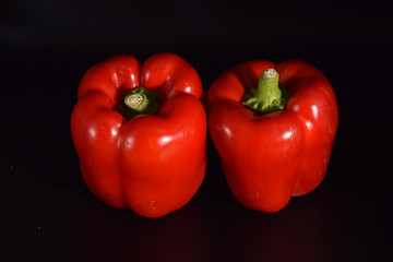 Bright red peppers on a seamless black background. 