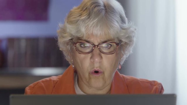 Senior woman looking very upset with what she sees on her computer