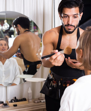 male makeup artist applying cosmetics for female