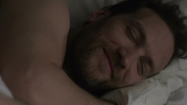 Adult man lying in bed, smiling before falling asleep, thinking about last date