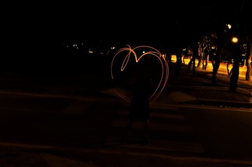 Young runner make the heart picture with red line on the road in the midnight