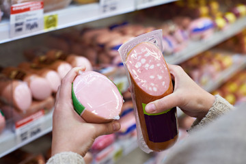 Woman chooses boiled sausage in grocery store