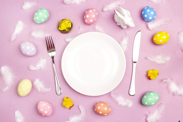 Easter table setting with cutlery and colorful eggs on violet table. Copy spase.