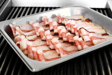 Neat rows of pre-cooked bacon slices on a tray