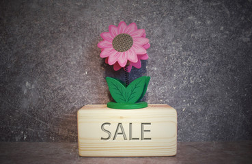 Business marketing concept. Wood block with flower and word sale on grey background.