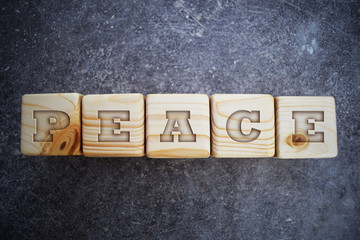 Peace - text on wooden texture blocks on grunge dark grey table