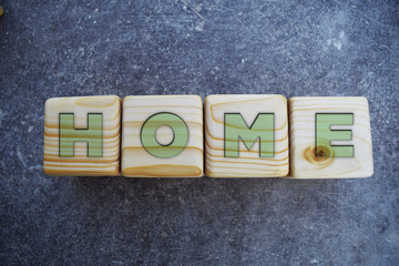 Home Text On Wooden Blocks on grey background. Blocks have light green letters.