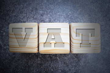 VAT - text on three  wood texture blocks on grunge dark grey table background.