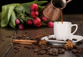 Pouring coffee from a Turkish coffee pot through a cup of coffee