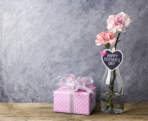 Mothers day concept of pink carnation flowers in clear bottle and gift box