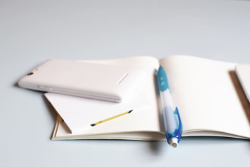 Office deskor table with notebook, smart phone, flash, pen. Top view with copy space. Working desk or school and study table. Accessories on light blue background. Concept of education or writing. 