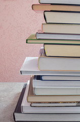 Stack of book on grunge gray brown table on light pink background. Education concept.
