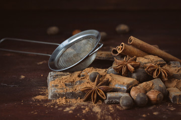 Chocolate, Spices, Spoon with Cocoa, Metal Strainer, Hazelnut on Dark Wooden Background. Copy space