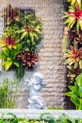Statue of Cupid in cozy garden on summer./  Statue of Cupid and water fall in cozy garden on summer.
