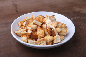Delicious crispy croutons, crumbs of bread in white plate. ready for cooking.