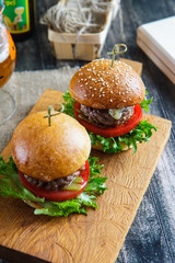 Tasty and appetizing hamburger cheeseburger on a wooden board side view
