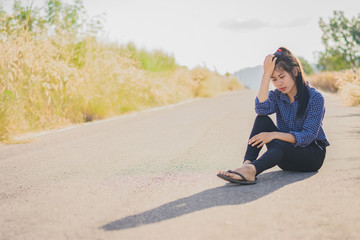 Fototapeta na wymiar Portrait beautiful Asian woman in depression and frustration sitting on road