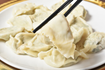 Boiled dumplings on chopsticks hold by human hand 