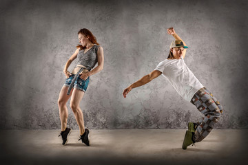 Hip Hop dancer in dynamic action jump on the grunge grey backgro