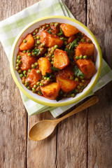 Home Indian food: Aloo Matar - potatoes, green peas and spicy sauce closeup. Vertical top view © FomaA