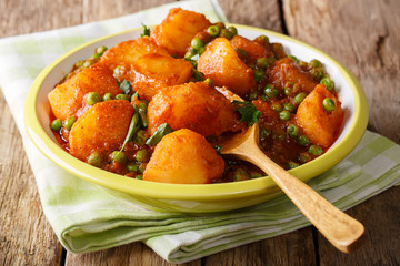 Vegetarian Indian Aloo Matar made from potatoes, green peas, herbs and spicy sauce closeup on a plate. horizontal