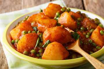 Indian hot Aloo Matar - potatoes, green peas, herbs and spicy sauce closeup on a plate. horizontal