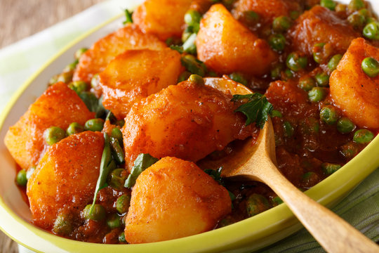 Spicy Aloo Matar potatoes, green peas and spices close-up on a plate. horizontal