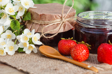 Traditional homemade strawberry jam in jars with fresh strawberries on wooden desk