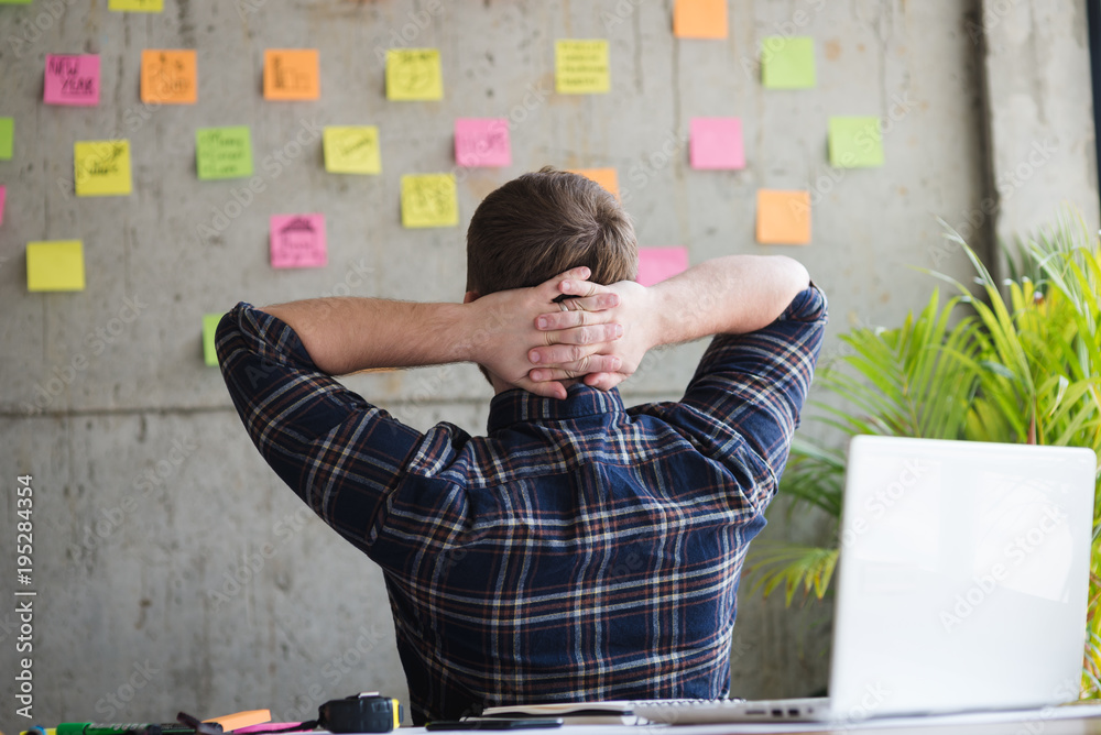 Wall mural back of entrepreneur sitting in office and look at colorful sticky message on cement wall. work life