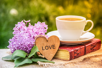 Cup of tea, lilac branch and  book. Spring time. Tea and book in the garden.