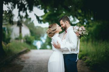 Romantic wedding moment, couple of newlyweds smiling portrait, bride and groom hug while on a walk in the park