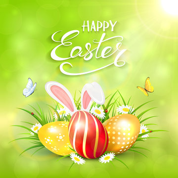 Green sunny background with Easter eggs and rabbit ears in grass