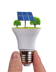 Hand holding eco LED light bulb with solar panel isolated on white background. Concept of green energy.