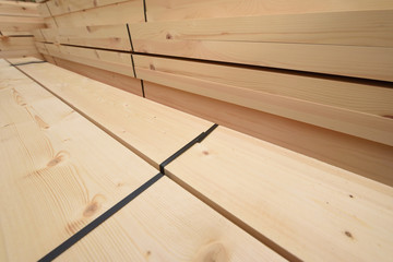 Many folded wooden planks in a warehouse with a forest