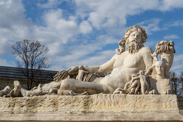 A statue of the Colossus Nile in the Jardin des Tuileries in Paris against a bright blue sky with white clouds